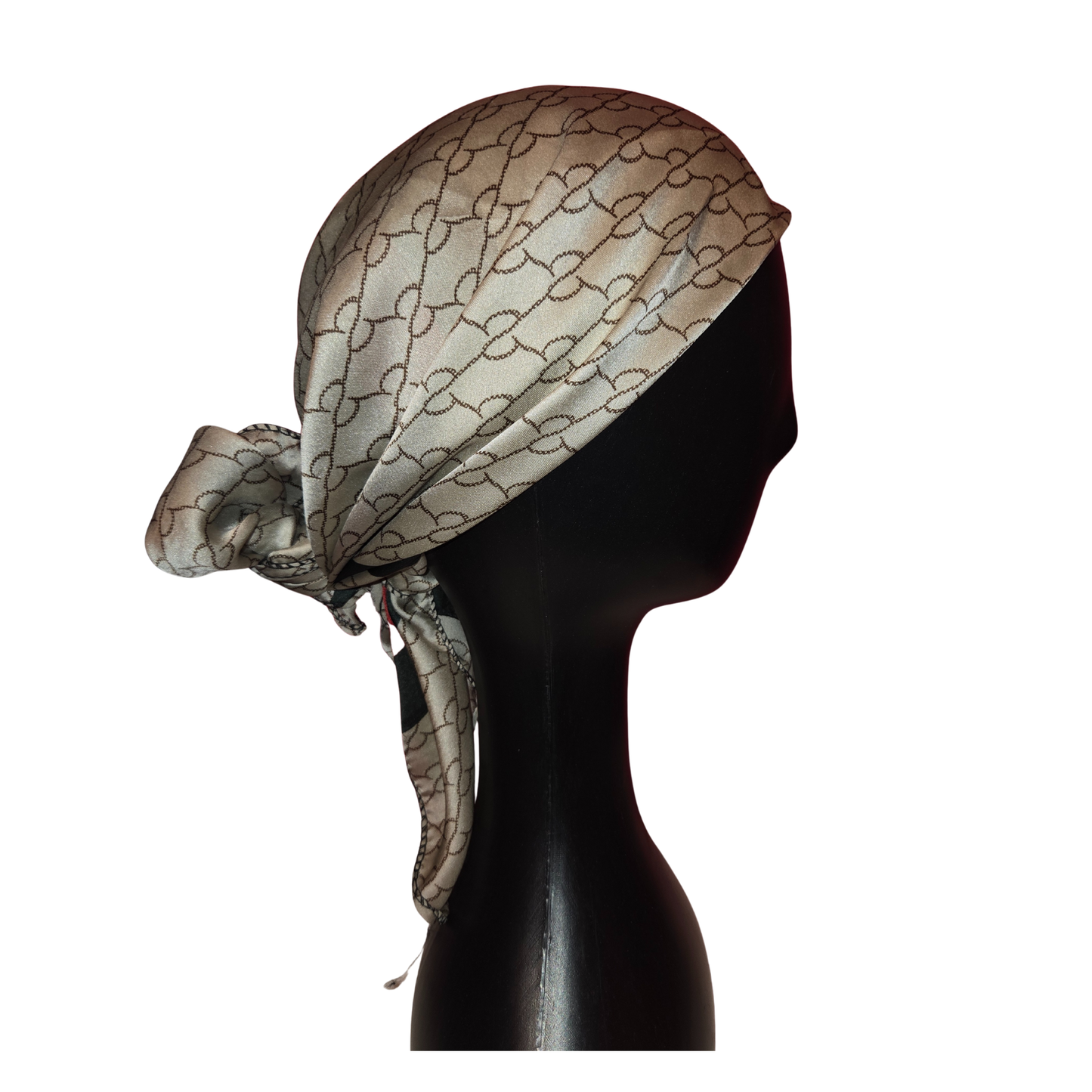 Beige headscarf with black pattern on a mannequin head against a white background