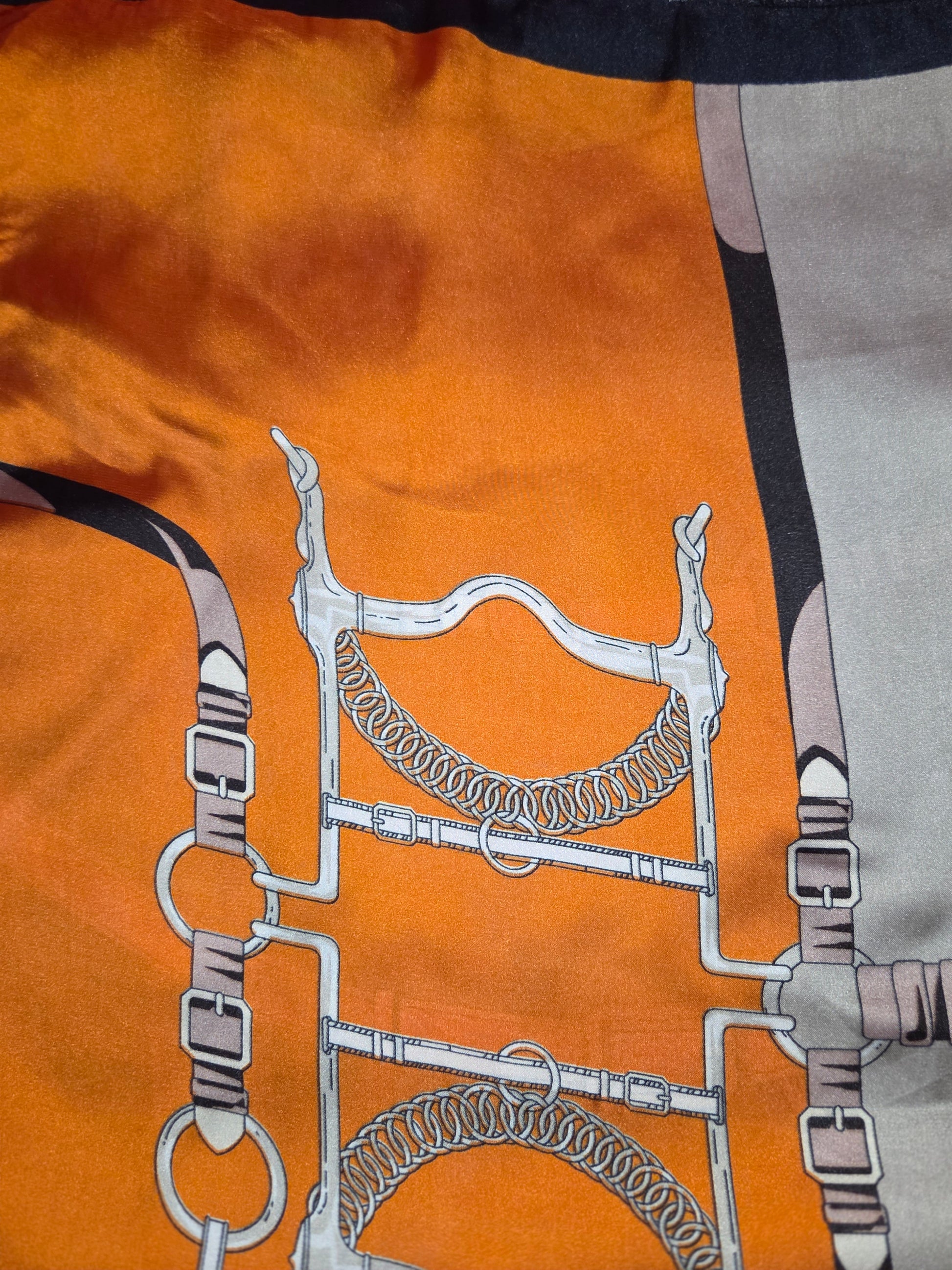 Close-up of a patterned fabric with horse bridle design on an orange background