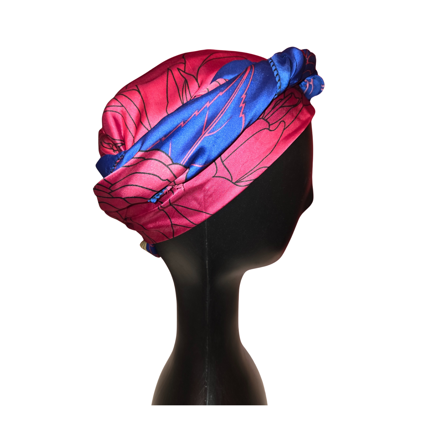 Mannequin head wearing a pink and blue patterned headscarf on a white background