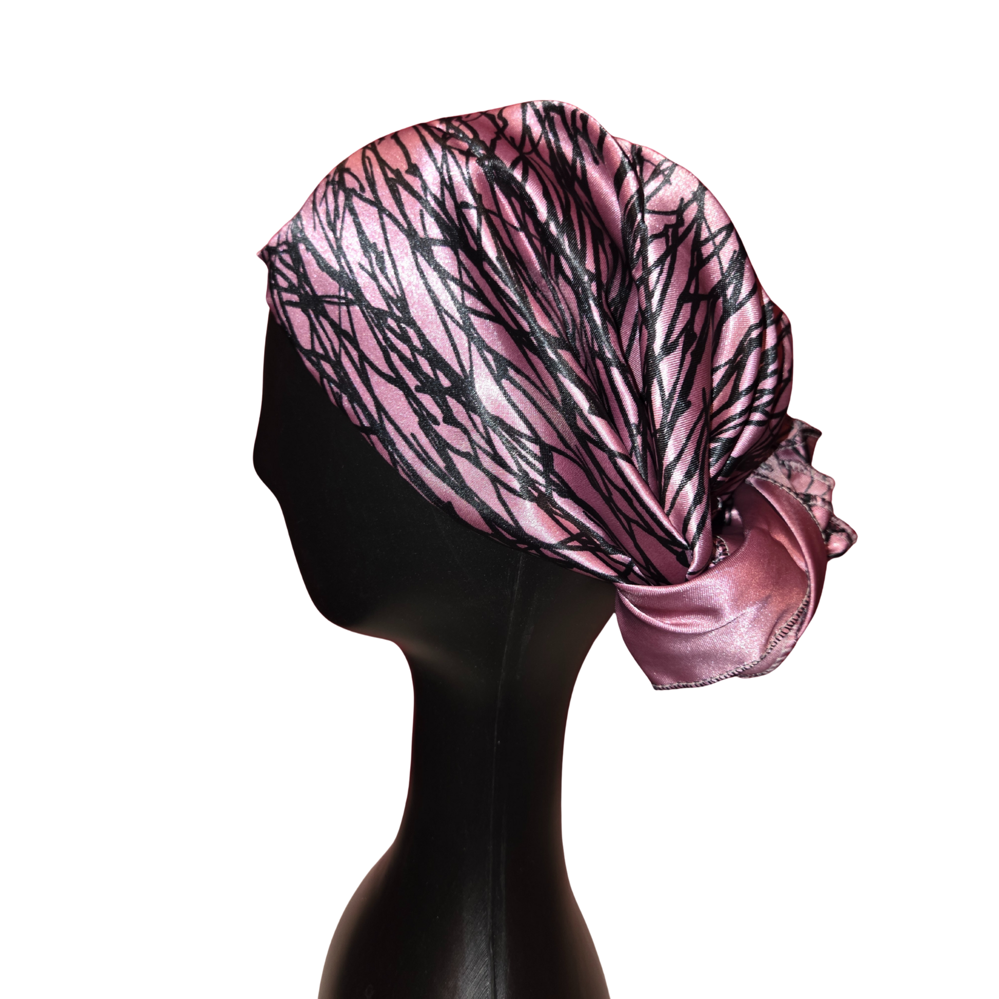 Pink headscarf with black abstract pattern on a mannequin head against a white background