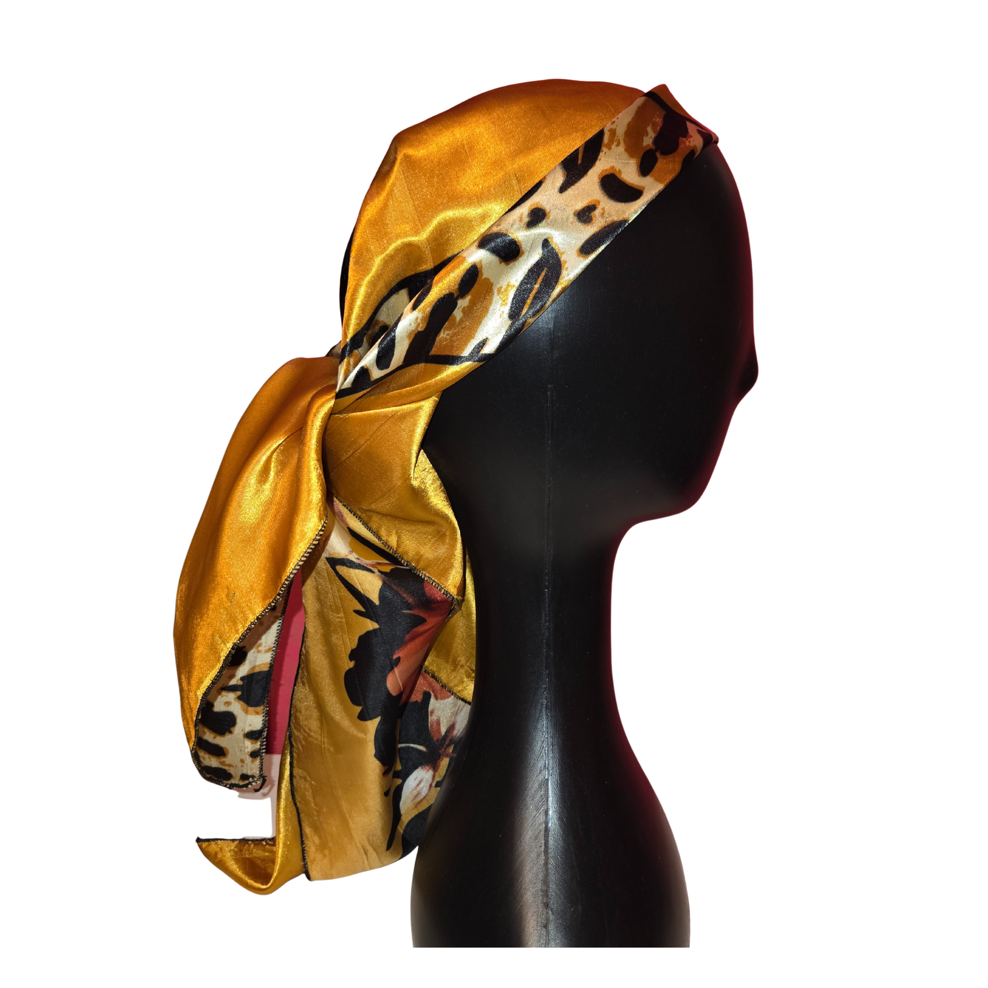 Mannequin head wearing a gold satin headscarf with butterfly and leopard print details on a white background